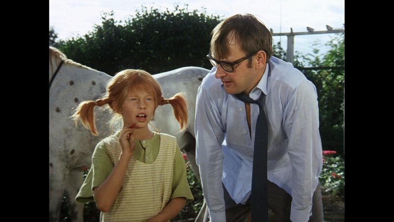 Pippi Langstrumpf (Inger Nilsson) zeigt dem abgekämpften Papa von Tommy und Annika nochmals, wie man Wurfpfeile ins Schwarze bringt. – Bild: ZDF/​Studio 100 Media