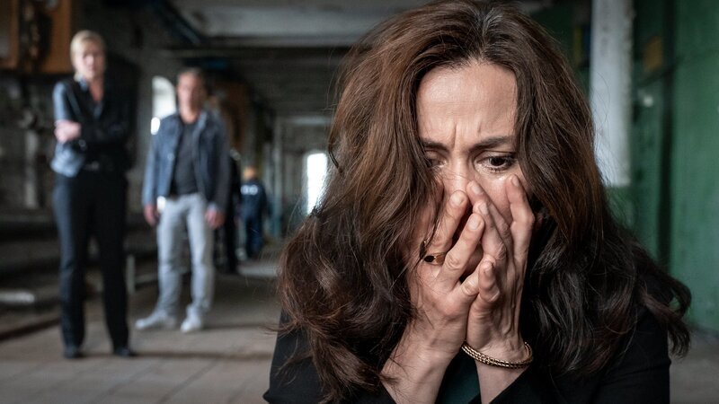 Als Dr. Dilan Soray (Idil Üner, r.) die Nachricht vom Tod ihres Sohnes erreicht, fährt sie unverzüglich zum Tatort. Als sie die Leiche ihres Sohnes sieht, sackt sie verzweifelt in sich zusammen. Ina Zimmermann (Melanie Marschke, l.) und Jan Maybach (Marco Girnth, M.) können ihr dabei keinen Trost spenden und stehen hilflos im Hintergrund. – Bild: ZDF