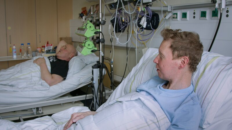 Nicole erwacht nach ihrer dramatischen Lebertransplantation, während sich der Zustand von Lars stetig verschlechtert. Er benötigt nun dringend ein Herz. Susanne spendet Carsten eine Niere und Mario Rosa-Bian ist enttäuscht von der Resonanz seiner Kampagne. Lars’ Zimmernachbarn Olaf und Jan, Wartepatienten im Paulinenkrankenhaus, erhalten eine schreckliche Nachricht. Olaf und Jan sind Zimmer- und Leidensgenossen. Zwischen den beiden Männern entwickelt sich während ihrer Wartezeit eine Freundschaft. – Bild: rbb/​DOCDAYS Productions