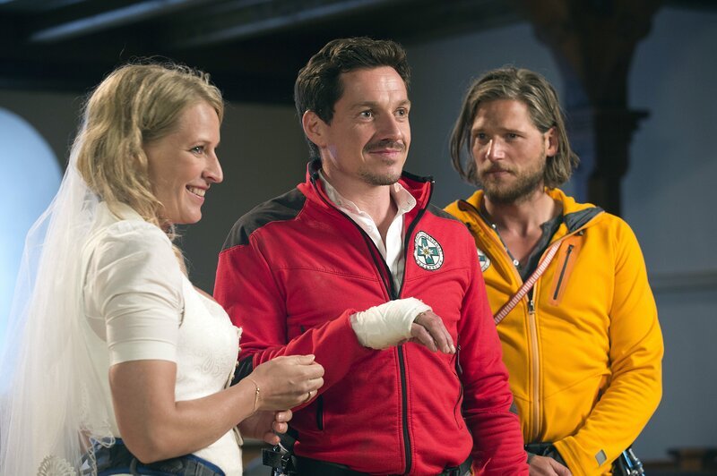 Markus Kofler (Sebastian Ströbel, r.) ist Trauzeuge bei der Hochzeit von Emilie (Stefanie von Poser) und Tobias (Markus Brandl, M.). – Bild: ZDF/​Thomas R. Schumann