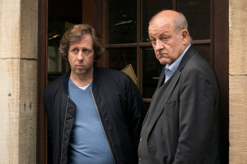 Ekki (Oliver Korittke, l.) und Wilsberg (Leonard Lansink, r.) beobachten das Geschehen vor dem Antiquariat. – Bild: Thomas Kost /​ ZDF