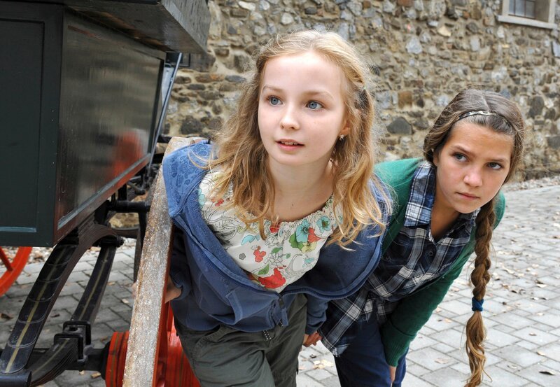 Lena (Kristina Yntema, l.) besucht mit ihrer Schulklasse das Gestüt. Dort schleicht sie sich heimlich mit einer Freundin (Lara Chommakh, r.) davon, um die jungen Pferde zu besuchen. – Bild: MDR/​ORF/​Hubert Mican