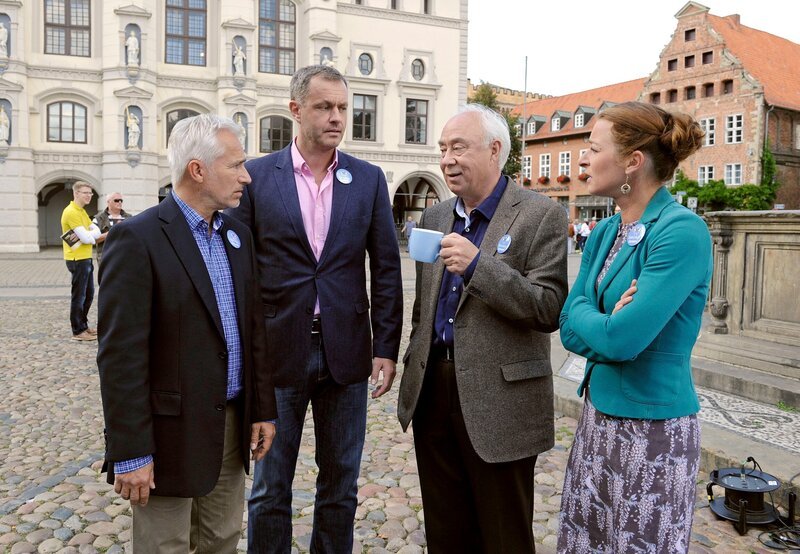 Thomas (Gerry Hungbauer, l. mit Komparsen, h.) ärgert sich über den populistischen Wahlkampf seines Konkurrenten und will in der Bildungsdebatte punkten (mit Joachim Kretzer, 2.v.l., Klaus Mikoleit, 2.v.r und Maria Fuchs, r.). – Bild: ARD/​Nicole Manthey