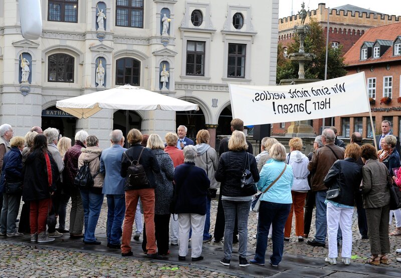 Thomas (Gerry Hungbauer, M.) hat sich mit seiner Aussage über minderwertige Arbeitsplatze selbst reingelegt. Tatsächlich erscheinen beim Straßenwahlkampf zu seinem Entsetzen Demonstranten, die ihn mit rohen Eiern bewerfen. – Bild: ARD/​Nicole Manthey