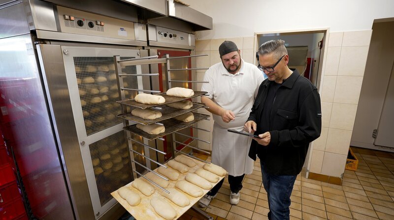 Gastro-Unternehmer Oliver Firla (rechts) bespricht mit Bäcker Andy Sankowski die Produktion für die nächsten Tage. Firla lässt sämtliche Backwaren in seiner eigenen Bäckerei frisch zubereiten. Über eine App auf seinem Tablet kann er die aktuellen Umsätze jederzeit einsehen. Die Digitalisierung seiner Betriebe ist eine wichtige Grundlage für den Erfolg seines Unternehmens. – Bild: NDR Gastro-Unternehmer Oliver Firla (rechts) bespricht mit Bäcker Andy Sankowski die Produktion für die nächsten Tage. Firla lässt sämtliche Backwaren in seiner eigenen Bäckerei frisch zubereiten. Über eine App auf seinem Tablet kann er die aktuellen Umsätze jederzeit einsehen. Die Digitalisierung seiner Betriebe ist eine wichtige Grundlage für den Erfolg seines Unternehmens. – Bild: NDR