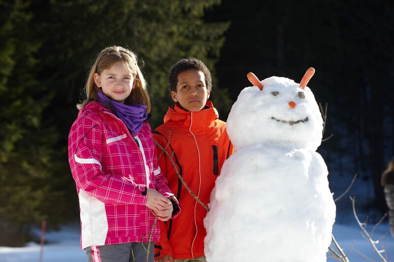 Nahas und Paula lassen sich mit ihrem gerade gebauten Schneemann fotografieren. – Bild: Walter Wehner
