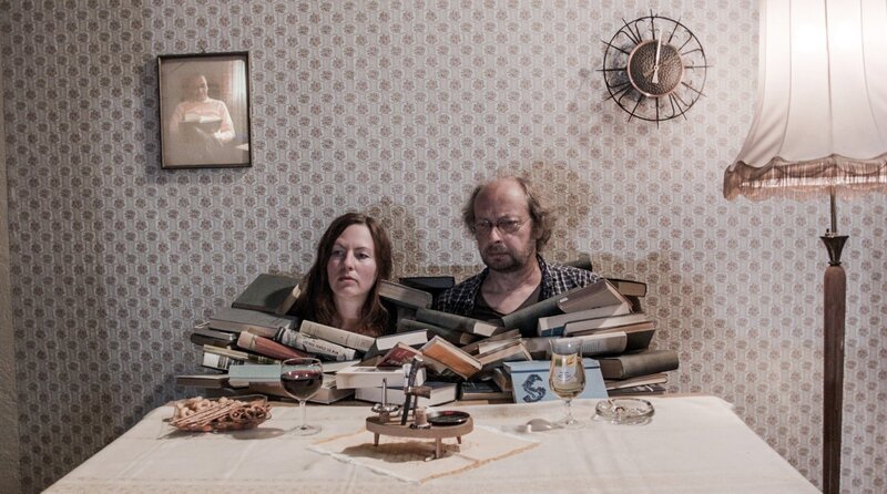 Mutter (Beate Düber) und Vater (Matthias Zwarg ) sitzen vor einem Berg Bücher. – Bild: MDR/​Domenik Schuster