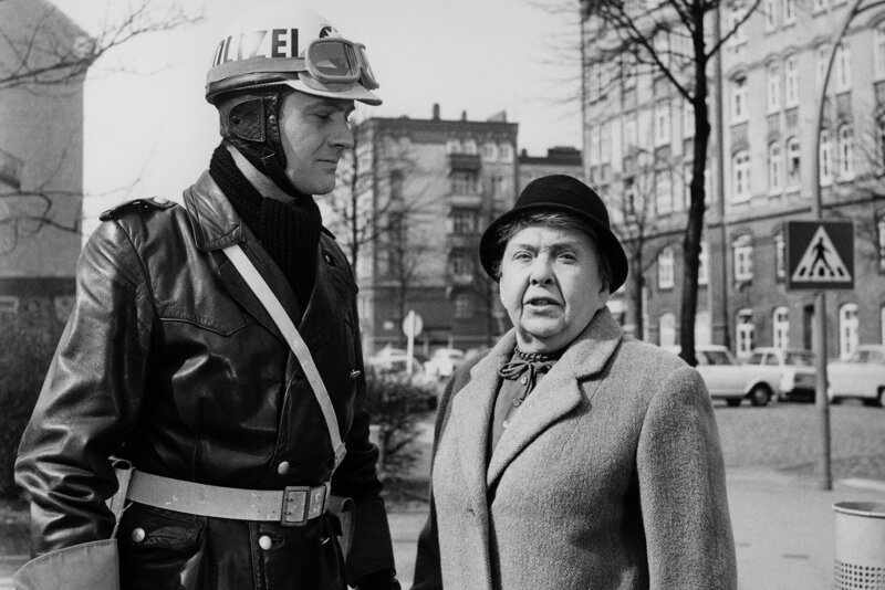 Als Freund und Helfer bewährt sich Streifenfahrer Hartmann (Karl-Heinz Heß) bei der Rentnerin Paula Henkel (Emmy Jülich), die ziemlich hilflos vor dem Straßenübergang steht. – Bild: NDR/​Klügel