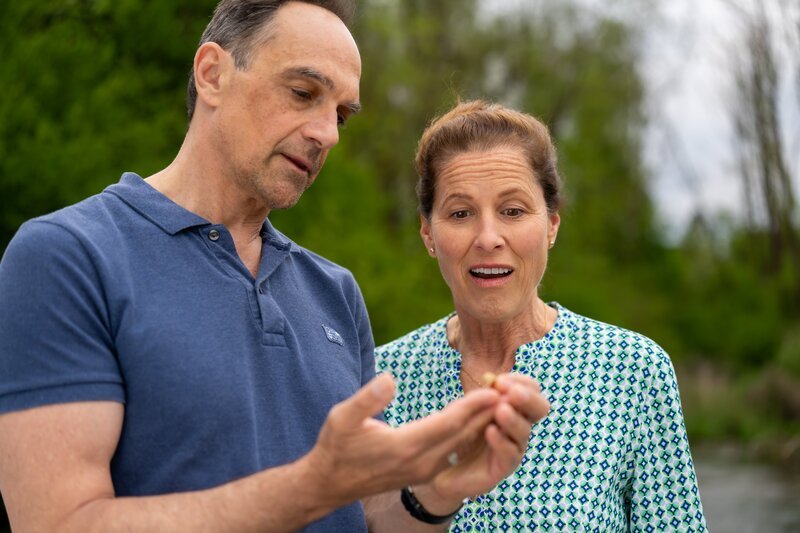 Mike (Harry Blank) und Annalena (Heidrun Gärtner) freuen sich, weil sie offenbar ein Stück Gold am Bach gefunden haben. – Bild: Ewa Wiese /​ BR
