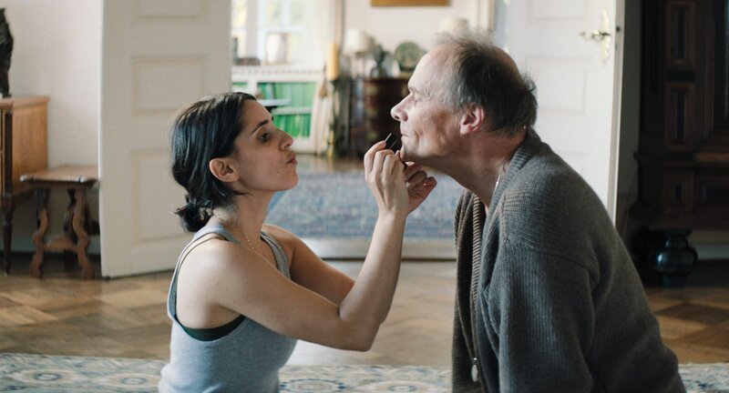 Leyla (Maryam Zaree), in Fabiennes Körper, trägt Stella (Edgar Selge) Lippenstift auf. Key Visual. – Bild: Ahmed El Nagar /​ Walker+Worm Film GmbH & Co. KG