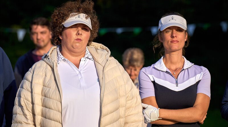 Der Minigolf-Wettkampf ist unterbrochen bis alle Anwesenden eine Schriftprobe abgegeben haben. Susanne Kurz (Marie Burchard, r.) und Olivia „Tiger“ Thomson (Thekla Viloo Fliesberg, l.) warten genervt. – Bild: ARD/​Frank Dicks /​ ARD-Programmdirektion