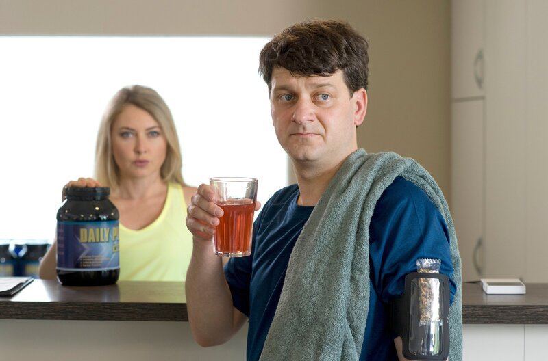 Daniel Schirmer (Sven Fricke, r.) trainiert in einem Fitnessclub und lässt sich von Trainerin Kristina (Malina Ebert, l.) zu dem Fitness-Drink „Daily-Plus mit Booster“ überreden. – Bild: ARD/​Thorsten Jander