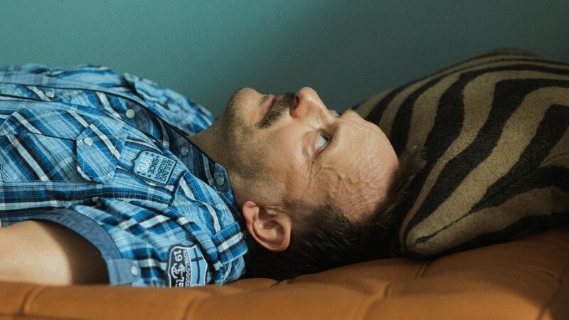Andi (Milan Peschel) fühlt sich auf der Liege im Praxisraum bei Therapeutin Alex Täubner plötzlich wohler als ihm lieb ist. – Bild: ZDF und Albrecht von Grünhagen