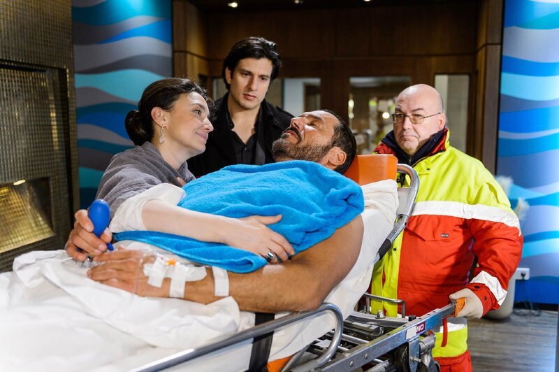 Richard (Silvan-Pierre Leirich, lieg.) wird, begleitet von Simone (Tatjana Clasing) und Maximilian (Francisco Medina), von dem Sanitäter (r. Komparse) in den Rettungswagen gebracht. – Bild: RTL /​ Willi Weber
