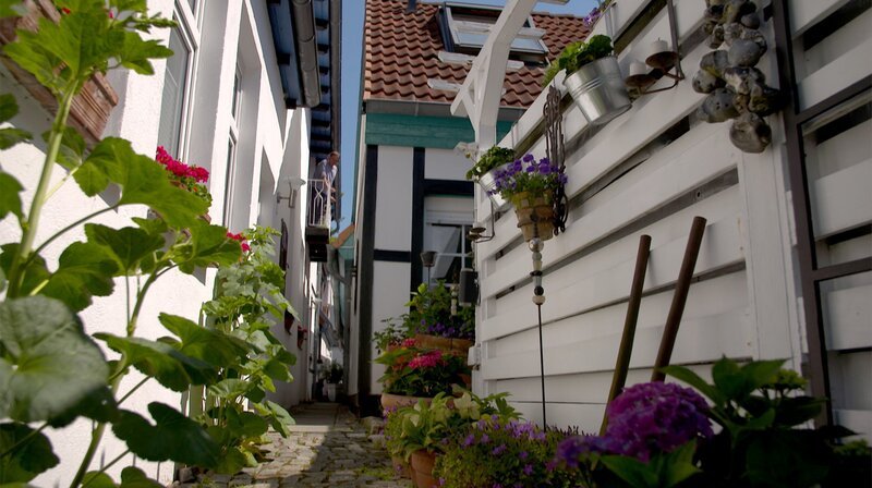 Der schmale Gang zwischen zwei Häusern heißt hier in Warnemünde „Tüsche“. Er musste so breit sein, dass eine schwangere Kuh durchpasst. – Bild: NDR