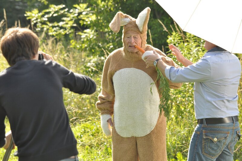 Im Hasenkostüm muss Alois Werbung für eine Gebisshaftcreme machen. Von links: Assistent (KLD), Alois Preissinger (Erich Hallhuber) und Fotograf Strixner (Adnan Erten). – Bild: BR/​Jo Bischoff