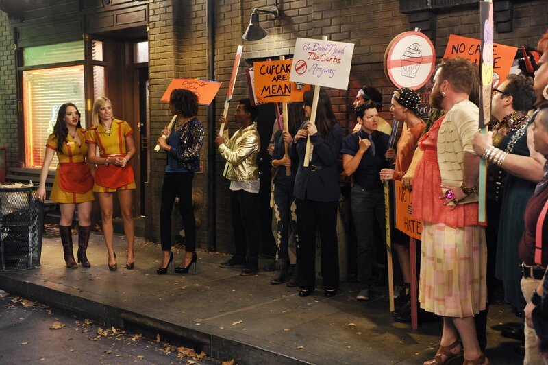 Sind Caroline (Beth Behrs, 2.v.l.) und Max (Kat Dennings, l.) wirklich schwulenfeindlich? Das behaupten zumindest die Demonstranten, die sich vor dem Diner und Cupcake-Shop versammelt haben … – Bild: Warner Brothers