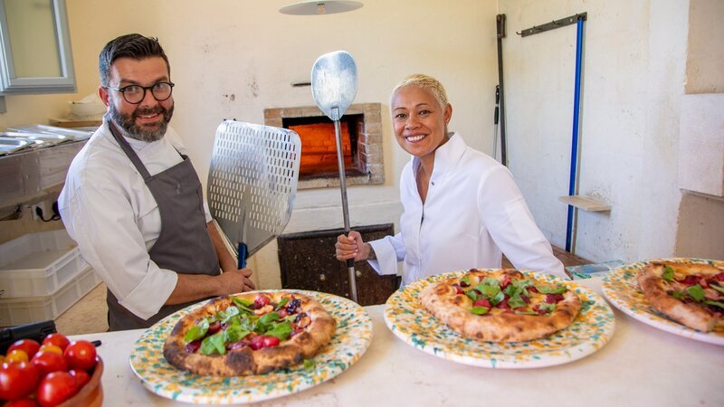 Moderatorin Monica Galetti bereitet mit Chefkoch Rocco Levante im Borgo Egnazia, Italien, Focaccia zu. – Bild: SRF/​BBC Studios