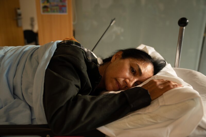 Niamh Kirby (Seeta Indrani) wartet im Krankenhaus auf die OP, mit der ihr der Pfeil aus dem Rücken entfernt wird. – Bild: BBC Studios /​ Red Planet Production /​ ZDF