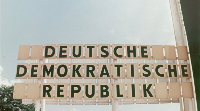Farb-Archivbild von einem Transitübergang für Autos zwischen Ost- und Westdeutschland 1970. Die Schilder bilden die Wörter "Deutsche Demokratische Republik". – Bild: BR/NORDPOLARIS GbR Farb-Archivbild von einem Transitübergang für Autos zwischen Ost- und Westdeutschland 1970. Die Schilder bilden die Wörter "Deutsche Demokratische Republik". – Bild: BR/NORDPOLARIS GbR