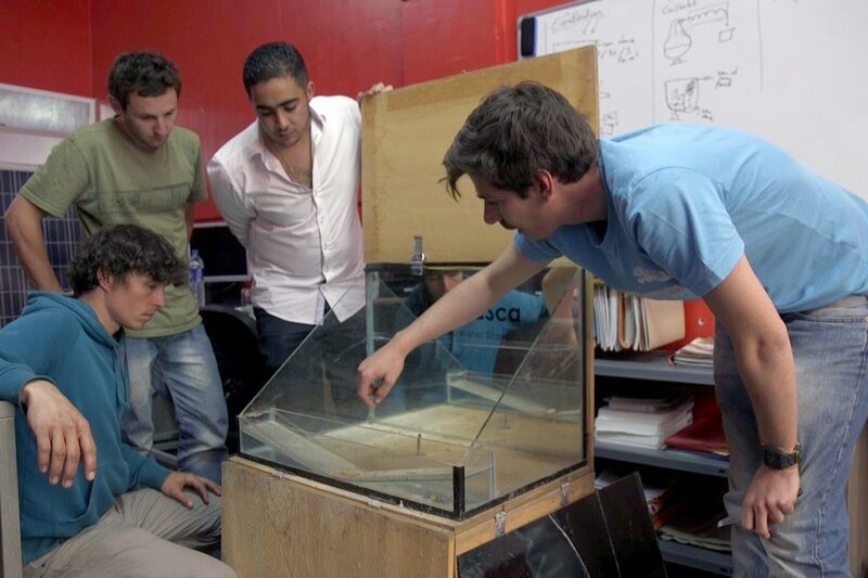 Younes (2.v.r.) und Mohamed Tahiri (re.) erläutern Corentin de Chatelperron (li.) und Gwénolé Gahinet (2.v.l.) ihren ersten Prototyp zur Trinkwassergewinnung aus Meerwasser. – Bild: Laurent Sardi /​ FL Concepts /​ ARTE France