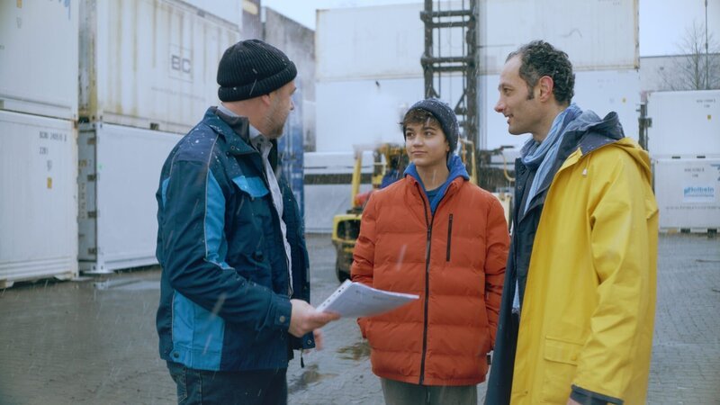 Hakim (Mads Albatros, Mitte) begleitet seinen Vater Esat (Haytham Hmeidan) zum ersten Arbeitstag in der Reinigungsfirma und trifft dabei auf den Chef (Christoph Tomanek). – Bild: NDR/​Boris Laewen
