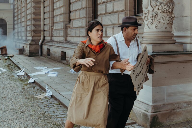 Frida Kahlo (Mina Sagdic) und ihr späterer Ehemann Diego Rivera (Christo Klahr) nehmen an der 1.Mai-Demo 1929 teil. – Bild: KiKA/​Sabine Finger