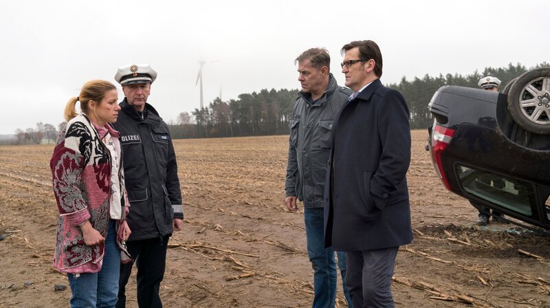 Finn (Sven Martinek, 2.v.r.) und Lars (Ingo Naujoks, r.) befragen Tanja Sanftrieder (Katrin Heß, l. mit Komparse), nach dem Unfallhergang. – Bild: WDR/​ARD/​Andreas Tams