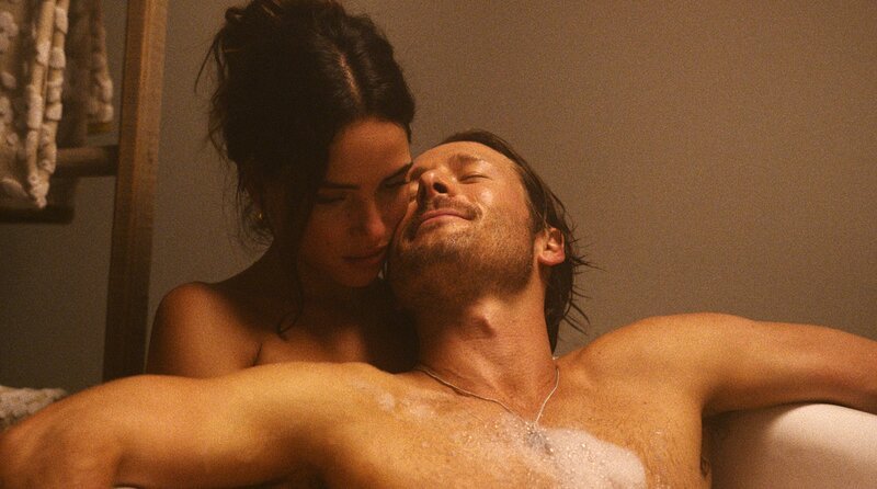 Als der Philosophielehrer und Aushilfs-Undercovercop Gary (Glen Powell) die geheimnisvolle Madison (Adria Arjona) kennenlernt, verlässt er seine Komfortzone und schlittert unter falschem Namen als „Ron“ in ein heißes Abenteuer. – Bild: Skip Bolen/​Brian Roedel /​ ZDF