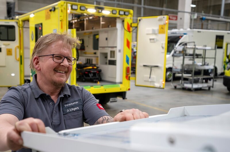 Sonderfahrzeugbau ist Millimeterarbeit. Dennis Lüken schiebt eine Trage in das neue Rettungsfahrzeug. – Bild: NDR/Dokness Sonderfahrzeugbau ist Millimeterarbeit. Dennis Lüken schiebt eine Trage in das neue Rettungsfahrzeug. – Bild: NDR/Dokness