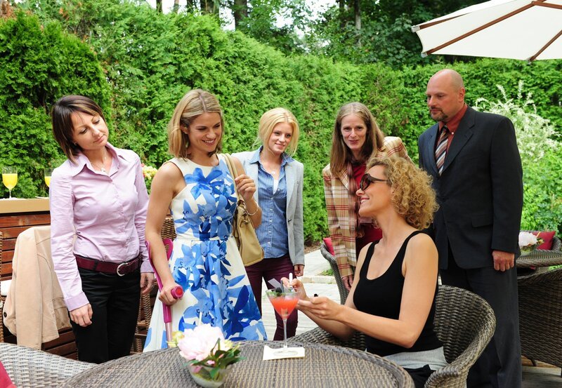 Um Natascha (Melanie Wiegmann, 2.v.r.) wieder aufzumuntern, lädt Marlene (Lucy Scherer, 2.v.l.) Fans (Komparsen) ein. – Bild: ARD/​Ann Paur