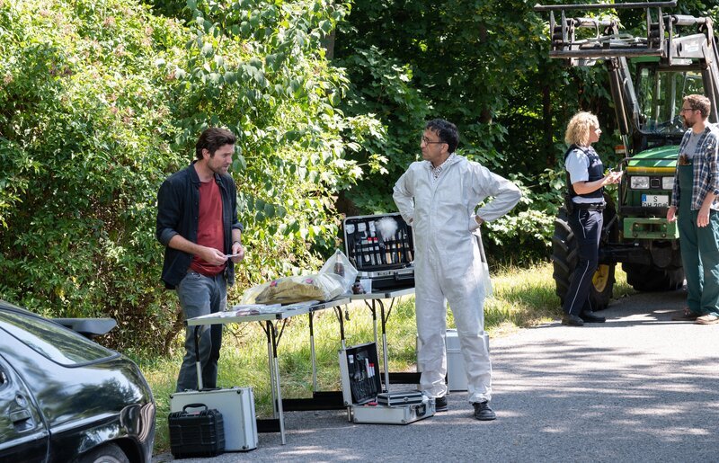 Ein 17-jähriges Mädchen ist spurlos verschwunden – nur ihr Rucksack wurde von einem Bauern (Komparse, r.) auf einer Landstraße gefunden. Eine Beamtin (Komparsin) befragt diesen, während KTU-Leiter Jan Arnaud (Mike Zaka Sommerfeldt, 2.v.l.) Kommissar Jo Stoll (Peter Ketnath, l.) die Fundstücke präsentiert. Ein Fall zwischen Hoffen und Bangen. – Bild: ZDF und MARKUS_FENCHEL