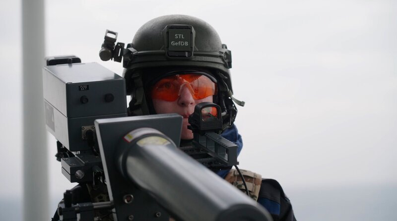 Eine Soldatin zielt mit einem Drone-Buster auf eine Drohne – Bild: Lennart Banholzer/​NDR