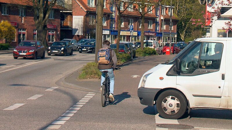 Ein Fahrradfahrer fährt knapp vor einem Transporter über die Straße. – Bild: NDR