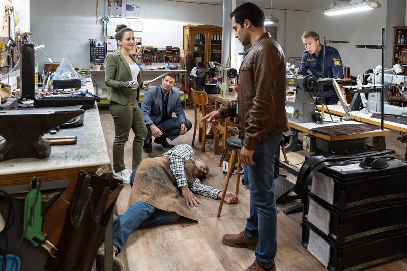 Pathologin Atay (Sevda Polat, l.) kann den Ermittlern Hansen (Igor Jeftić, 2.v.l.) und Kaya (Baran Hêvî, 2.v.r.) sowie Polizeihauptmeister Mohr (Max Müller, r.) bereits am Tatort sagen, dass das Opfer (Komparse, M.) mit einem Polsterpilz getötet wurde. – Bild: ZDF und Linda Gschwentner