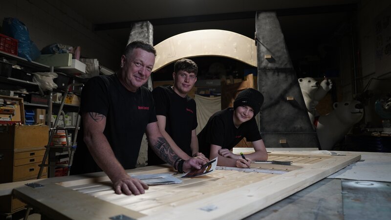 Kulissenbauer Angelo Zannin (l.) und seinen Söhne bauen das Eingangstor aus den „Jurassic Park“-Filmen nach. – Bild: Stella Ulrich /​ Cineteam Hannover /​ ZDF