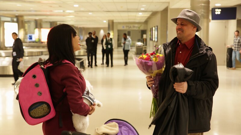 Jasmine holds Coco at the airport while Gino presents her with flowers. – Bild: Warner Bros. Discovery, Inc. or its subsidiaries and affiliates