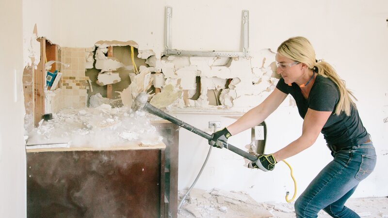 Jasmine Roth takes a sledgehammer to the cabinets in the kitchen during demolition. – Bild: HGTV