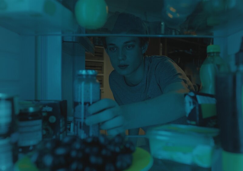 Aaron (Philip Müller) sucht im Kühlschrank nach dem Tomatensaft. – Bild: KiKA/​2021 eitelsonnenschein