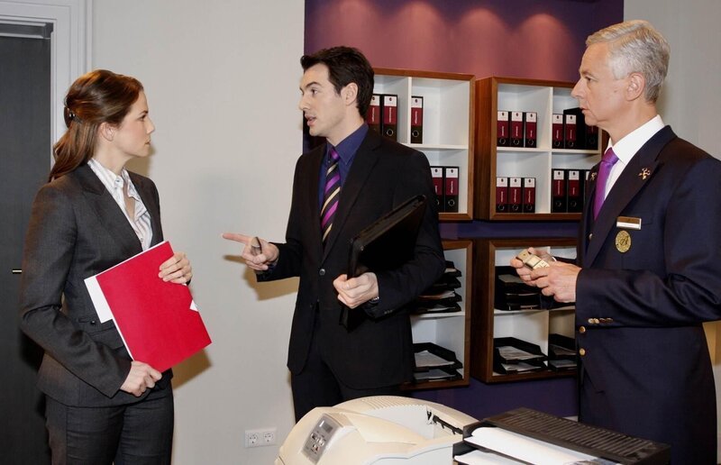 Als Mark (Arne Stephan, M.) der Verlegung des Concierge-Meetings ins „Aden“ eine Absage erteilt, muss Marcel (Thomas Engel, r.) befürchten, dass er seine südamerikanische Prinzessin niemals sehen wird. Karin (Birge Funke, l.) kann das nicht verstehen … – Bild: Noreen Flynn