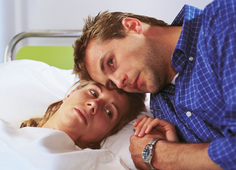 Lollo (Isabella Schmid) wacht aus der Narkose auf. Daniel (Rainer Frank) bangt mit ihr: War der Tumor bösartig? – Bild: RTL Deutschland