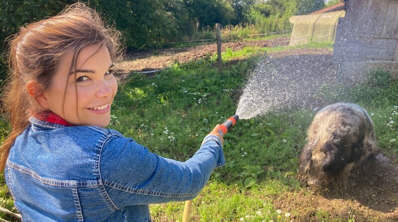 Sau Betti braucht an heißen Tagen eine kalte Dusche. Anna ist nur allzu gerne behilflich. – Bild: BR/​Text und Bild Medienproduktion GmbH & Co. KG