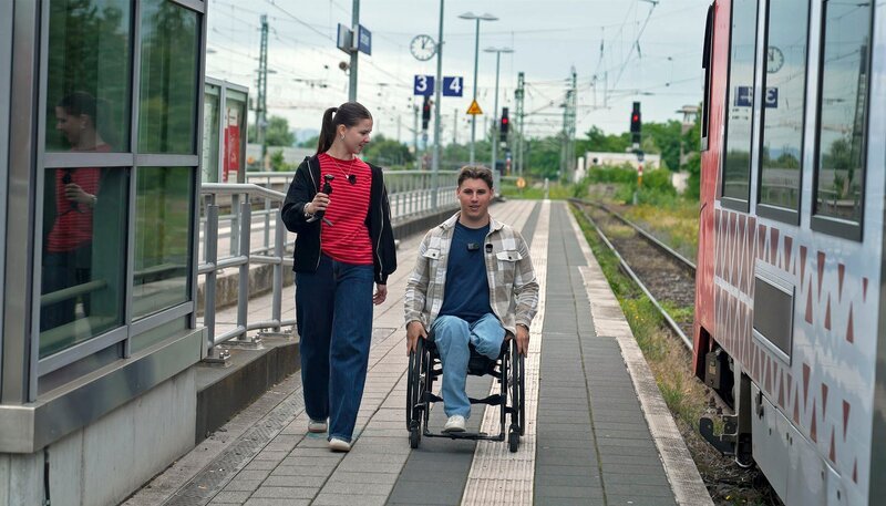 Nach einem Unfall sitzt Tom im Rollstuhl. Beim einfachen Ausflug zum Restaurant zeigt er POV-Host Helena, wie er im Alltag unzählige Barrieren überwindet. – Host Helena und Protagonist Tom – Bild: WDR/​WeAreEra