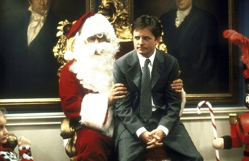 Mike (Michael J. Fox, r.) wird vom Nikolaus Winston (Barry Bostwick, l.) auf den Schoß genommen. – Bild: ProSieben Fun