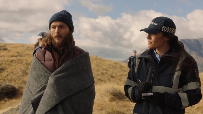 Cody Palmer (Milo Cawthorne) wird von Senior Constable Hoana Rata (Roimata Fox) befragt, nachdem sein Mitcamper auf kuriose Weise ums Leben gekommen ist. – Bild: ZDF und Emma Jones