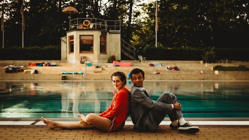 „Für immer Freibad“: Simon (Tyrell Otoo, r.) folgt brav den Zukunftsplänen seines Vaters, bis er sich im ortsansässigen Freibad in Rettungsschwimmerin Mira (Anouk Elias, l.) verliebt und der Sommer seines Lebens beginnt. – Bild: Xiomara Bender /​ ZDF und Xiomara Bender /​ Honorarfrei – nur für diese Sendung inkl. SocialMedia bei Nennung ZDF und Xiomara Bender