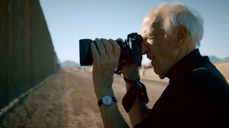 Im Jahr 2017 erhielt der Fotograf Thomas Hoepker die Diagnose Alzheimer. Während seine Fotokunst zu einem kollektiven Gedächtnis wurde, entschwindet ihm allmählich sein eigenes. Sein letzter großer Traum: Ein Roadtrip durch die USA mit seiner Ehefrau. Eine Neuauflage jener Reise, die seine internationale Karriere als Fotograf begründet hat. – Thomas Hoepker vor dem Grenzzaun zwischen den USA und Mexiko in Douglas, New Mexico. – Bild: rbb/NDR/GRANVISTA Media/DCM/Florian Mag Im Jahr 2017 erhielt der Fotograf Thomas Hoepker die Diagnose Alzheimer. Während seine Fotokunst zu einem kollektiven Gedächtnis wurde, entschwindet ihm allmählich sein eigenes. Sein letzter großer Traum: Ein Roadtrip durch die USA mit seiner Ehefrau. Eine Neuauflage jener Reise, die seine internationale Karriere als Fotograf begründet hat. – Thomas Hoepker vor dem Grenzzaun zwischen den USA und Mexiko in Douglas, New Mexico. – Bild: rbb/NDR/GRANVISTA Media/DCM/Florian Mag