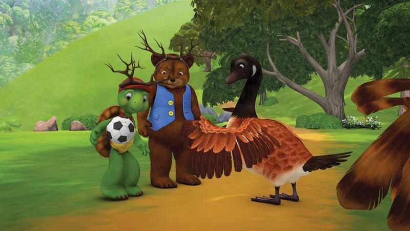Franklin und Bär streifen mit einem Geweih aus Ästen auf dem Kopf durch den Wald und spielen Elchsaurier. – Bild: KiKA/​Nelvana Limited/​Infinite Frameworks Pte Ltd.
