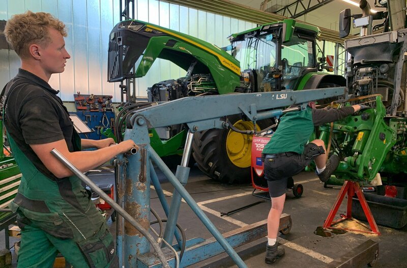 Mit Körperkraft und Werkstatt-Kran wird die Fronthydraulik an einen Traktor montiert – Bild: NDR