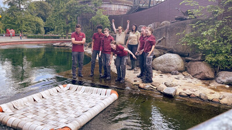 Emilio, Samuel, Luca, Lina, Christoph Urban, Meriam Pietsch, Leonie und Anuk lassen selbstgebautes Seelöwenfloß zu Wasser im Seelöwengehege des Zoo Leipzigs. – Bild: MDR/​Cine Impuls Leipzig GmbH